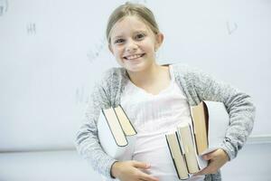 porträtt av Lycklig skol bärande böcker i klass foto