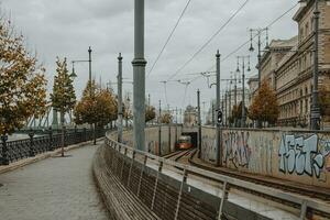 känd gul spårvagn gående ut av de tunnel i budapest under de molnig höst morgon- med frihet bro i de bakgrund foto