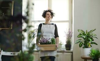 Lycklig ung kvinna innehav blommor i en kartong låda i en små affär foto