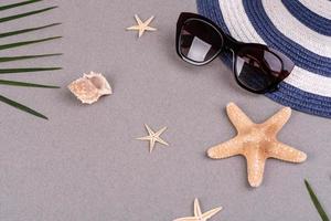 strandtillbehör, glasögon och hatt med skal och havsstjärnor på en färgad bakgrund. sommar bakgrund foto