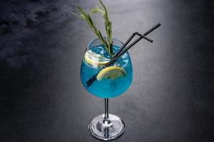 alkoholhaltig cocktail blå curacao med is, citron och cocktailrör foto