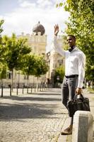 ung afrikansk amerikansk affärsman som väntar en taxi på en gata foto
