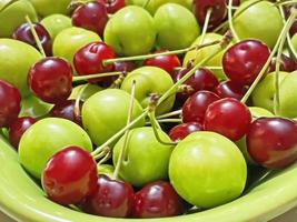 redo att äta och tvättade surkörsbär och plommon på en grön tallrik