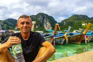 turist på koh phi phi ö thailand med lång svans båtar. foto