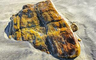gul orange röd sten sten på de strand sand i Mexiko. foto