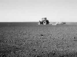 plogade fält förbi traktor i svart jord på öppen landsbygden natur foto