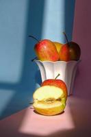 foto av ett äpple i en behållare på en rosa och blå bakgrund