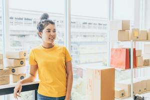 asiatisk kvinnaföretagare som arbetar hemma med förpackningslådan på arbetsplatsen - online-shopping sme-entreprenör eller frilansarbetsbegrepp foto
