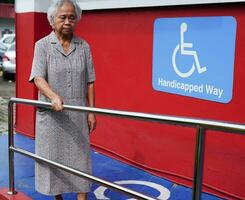 asiatisk äldre gammal kvinna patient använda sig av Stöd järnväg på ramp, ledstång säkerhet hugg bar, säkerhet i amning sjukhus. foto