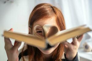 en flicka är innehav en bok. hjärtformade sidor. läsning, menande, inlärning foto