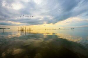 soluppgång över songkhla sjö reflekterande de gyllene ljus av himmel, thailand foto