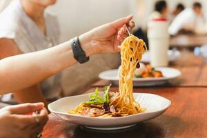 kvinna äter spaghetti med vän i restaurang. foto