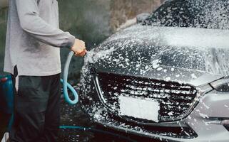 oidentifierad man tvättning en bil med hög tryck skum. foto