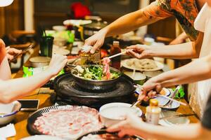 grupp av vänner matlagning de kinesisk shabu köttgryta på Hem. foto
