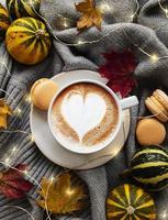 kopp kaffe, torra löv och halsduk på ett bord foto