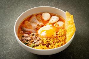 äggnudlar med fläsk och köttbulle i kryddig soppa eller tom yum nudlar i asiatisk stil foto