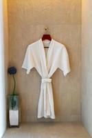 vit morgonrock som hänger på väggen i badrummet foto