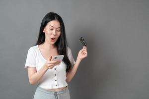 ung asiatisk kvinna som använder telefonen med handen som rymmer kreditkortet - online shoppingbegrepp foto