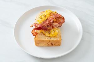 brödskål med äggröra och bacon på den vita plattan foto