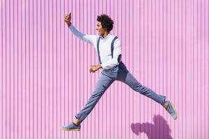 svart man tar en selfie med sin smartphone medan han hoppar utomhus.