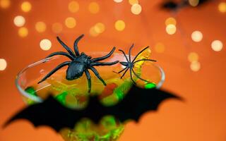 halloween grön cocktail med svart spindlar, godis maskar och en fladdermus. festlig fest. närbild. selektiv fokus. foto