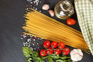 pasta och matlagning ingredienser på svart skiffer bakgrund. foto
