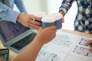 lag ingenjörer, arkitekter och verklig egendom investerare karnade över kopp av varm kaffe till gratulera dem deras framgångsrik projekt design inom budget. varm kaffe krock begrepp till fira i kontor foto