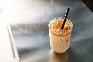 hög vinkel se av ett iced kaffe latte med sugrör på en stål disken topp i kaffe hus. foto