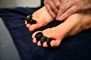 närbild av kvinnas fötter tar emot varm sten massage i ayurvediska wellness spa-resort foto
