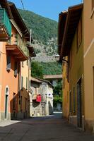 tömma gränd och färgrik byggnader och en gård med mång färgad flaggor, i italiensk medeltida stad canzo i lombardiet. foto