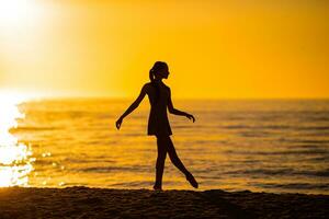 Lycklig tonåring flicka njut av tropisk strand semester på solnedgång foto