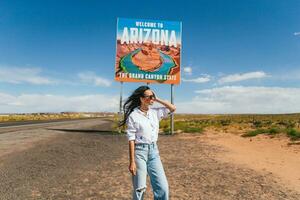 skön kvinna på henne resa till de USA på de bakgrund av Välkommen till arizona stat gräns tecken rätt i de paje kanjon, USA foto