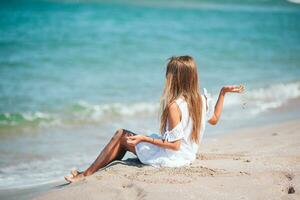 liten förtjusande flicka spelar på strand med sand foto