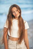 förtjusande ung flicka med skön lång hår njut av tropisk strand semester. de flicka på de havsstrand på solnedgång foto