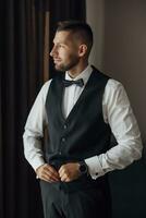 morgon- av en eleganta brudgum, man, i en svart kostym och slips, hans förberedelser på de hotell, i en Foto studio, fastsättning knappar och jacka, porträtt