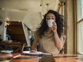 attraktiv tjej sitter på ett kafé vid bordet och dricker kaffe