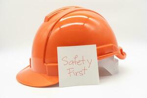 orange säkerhet hatt med meddelande säkerhet först. hård hatt isolerat på vit bakgrund. foto