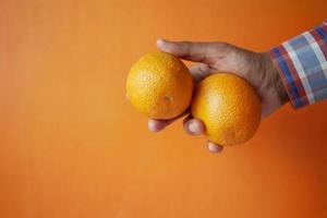 manhand som håller skivan av orange frukt jag mot orange bakgrund foto