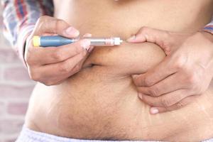 ung manhand med hjälp av insulinpenna på nära håll