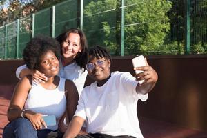 glada tjejer av olika nationaliteter tar selfies på sommaren foto