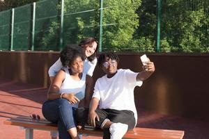 glada tjejer av olika nationaliteter tar selfies på sommaren foto