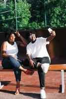två glada afroamerikanska kvinnor tar selfies på gatan