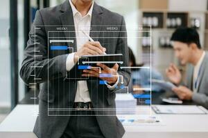 projektledare som arbetar och uppdaterar uppgifter med milstolpar framstegsplanering och Gantt-diagram schemaläggningsdiagram. företag som arbetar med smart telefon, surfplatta och bärbar dator på kontoret. foto