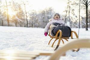 Lycklig flicka på släde i vinter- landskap foto