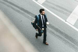 affärsman med hämtmat kaffe och skateboard gående på de gata foto