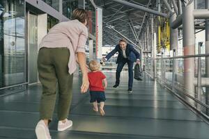 Lycklig barn löpning in i vapen av reser affärsman på de flygplats foto
