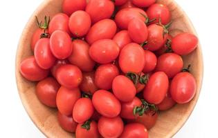 färska tomater i träskål på vit bakgrund