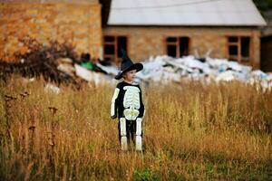 liten pojke bär en skelett kostym och en svart hatt . halloween Semester. foto