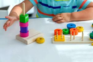 närbild av en liten pojke är hand är spelade med färger leksaker. pedagogisk logik trä- leksaker för barn. foto
