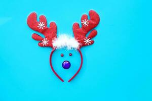 jul ren begrepp tillverkad från ring med rådjur horn, röd dekoration leksak på blå bakgrund. platt lägga topp se . foto